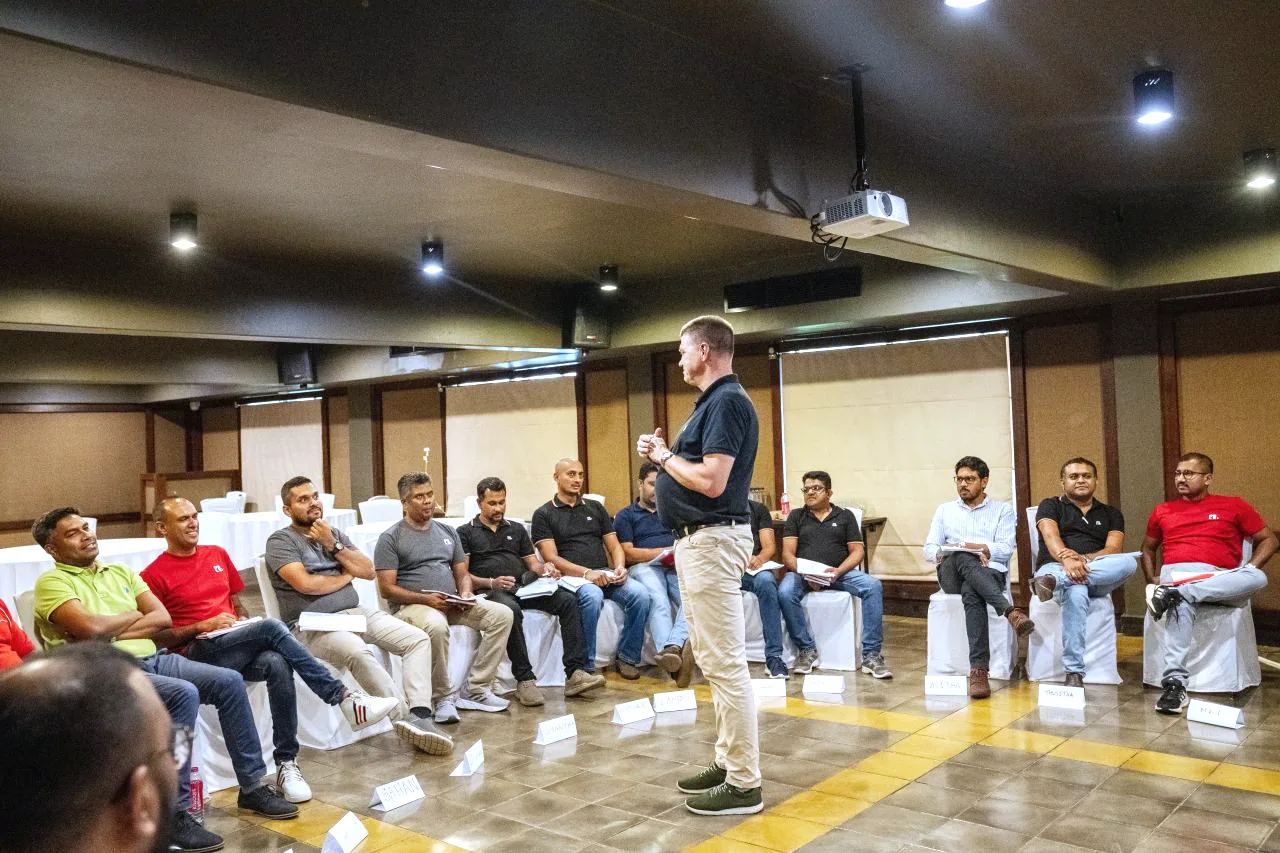 Team leads seated in a circle while the trainer speaks in the middle