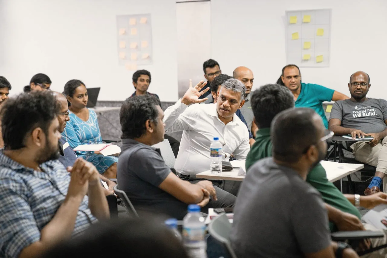 Team leads in discussion around tables during a leadership workshop