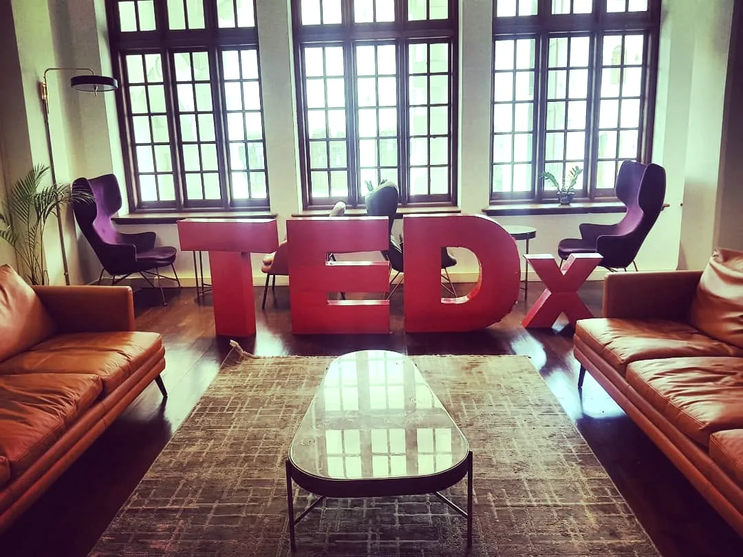 A lounge with large red TEDx letters in front of tall windows
