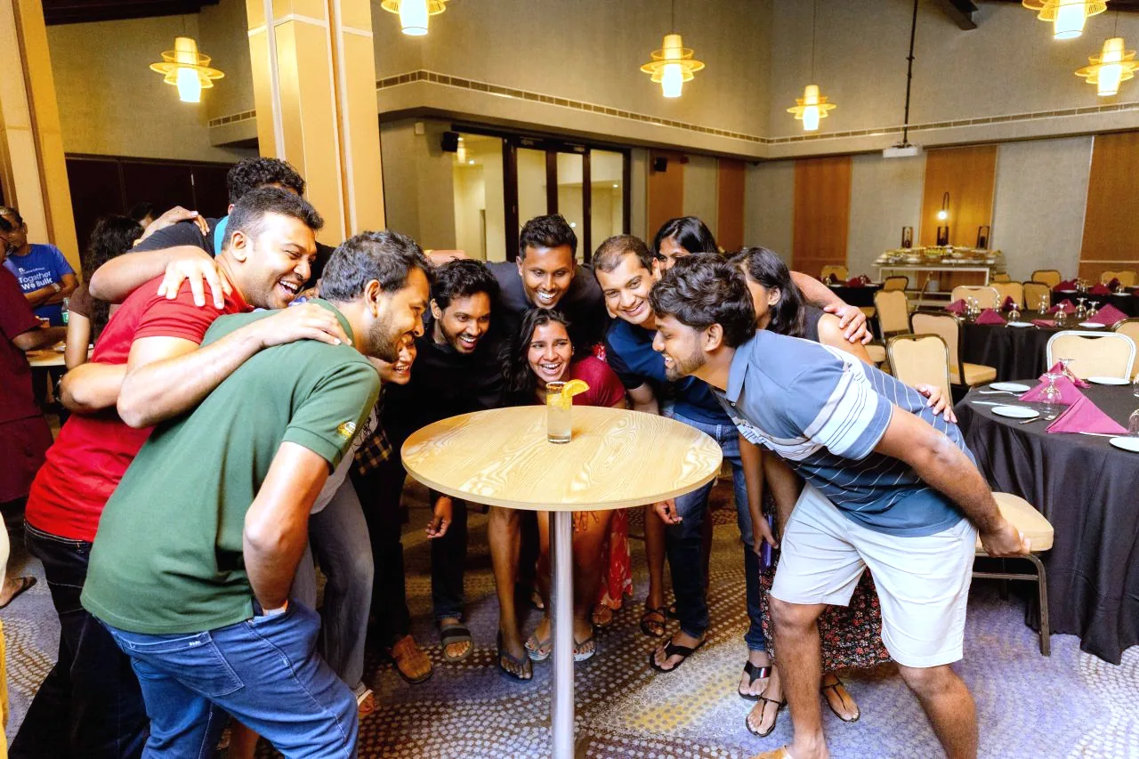Colleagues huddled and laughing around a table during an evening team game